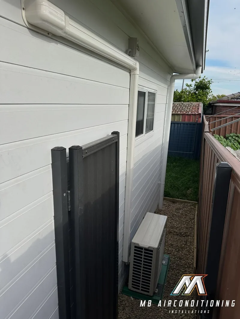 Condenser unit installed beside a fence line with maintenance access kept clear