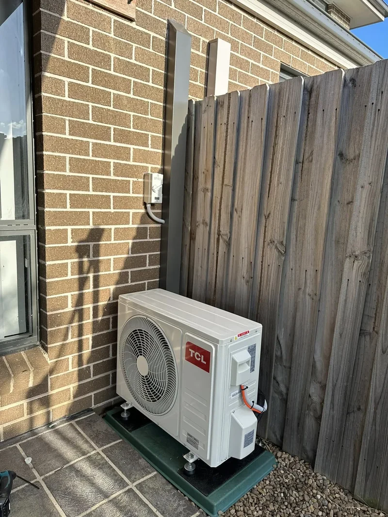 Outdoor condenser unit installed on a paved side path, ready for servicing access