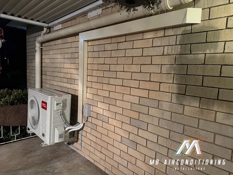 Condenser unit mounted on a brick wall with tidy pipework and clearance for service