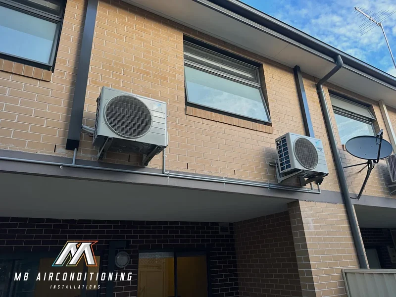 Multiple condenser units installed across a two storey strata unit block